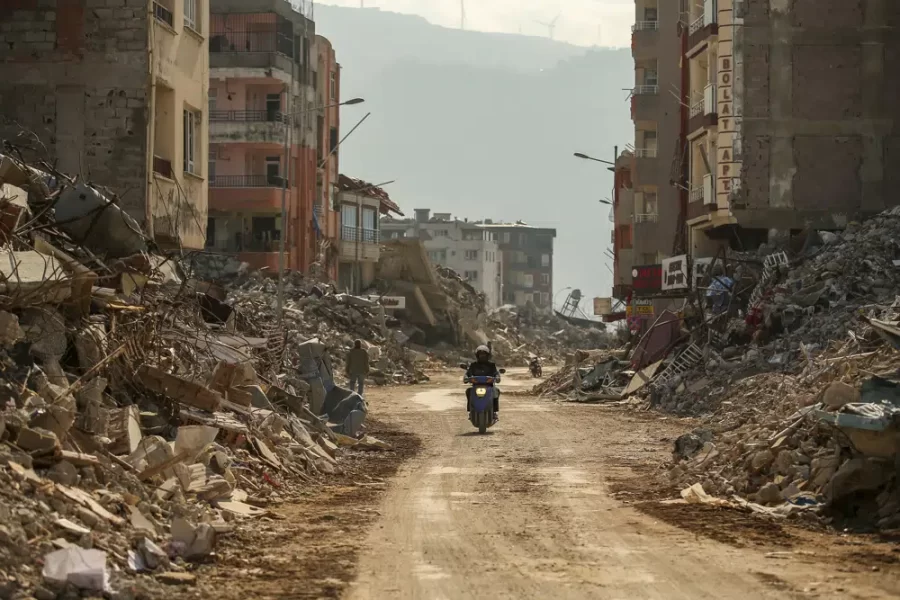 A man in Samandag, a city in southern Türkiye, rides his motorcycle down a devastated road.

Credit: AP Photo/Emrah Gurel