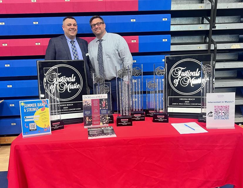 Mr. Landini 01 and Mr. Bickel 95 pose with various awards the music program has won of the years at DeMathas New Student Welcome in April.